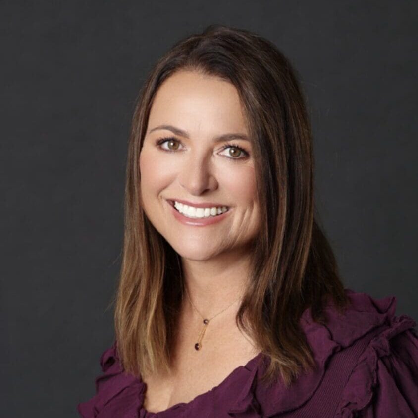 A woman in purple shirt smiling for the camera.